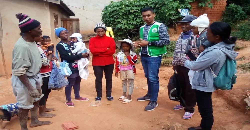 Un animateur d’EDENa en gilet vert échange avec des familles devant leur maison