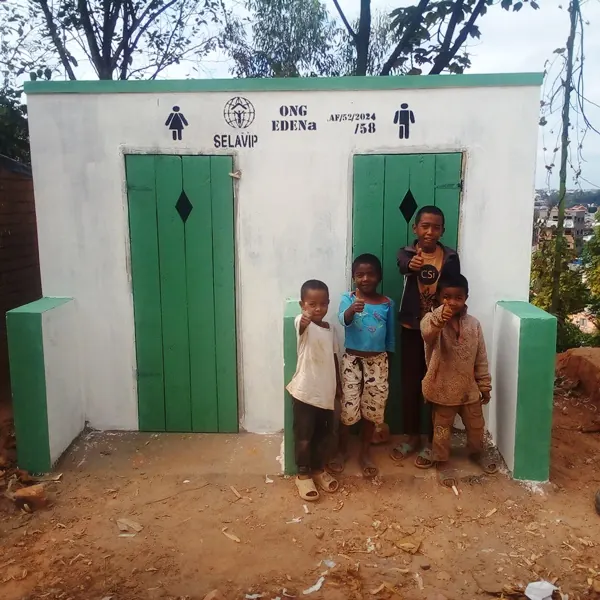 Une latrine communautaire aux portes vertes, entourée d’enfants